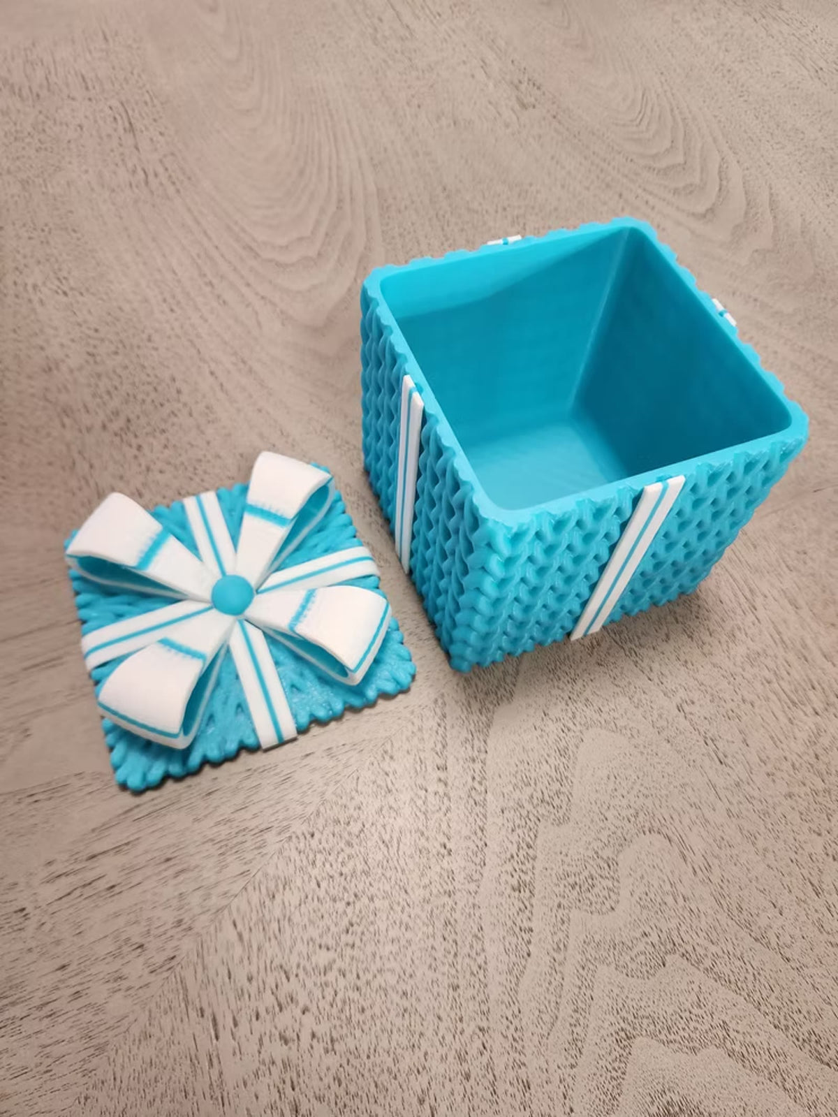 Teal knitted gift box with the bow lid set beside it