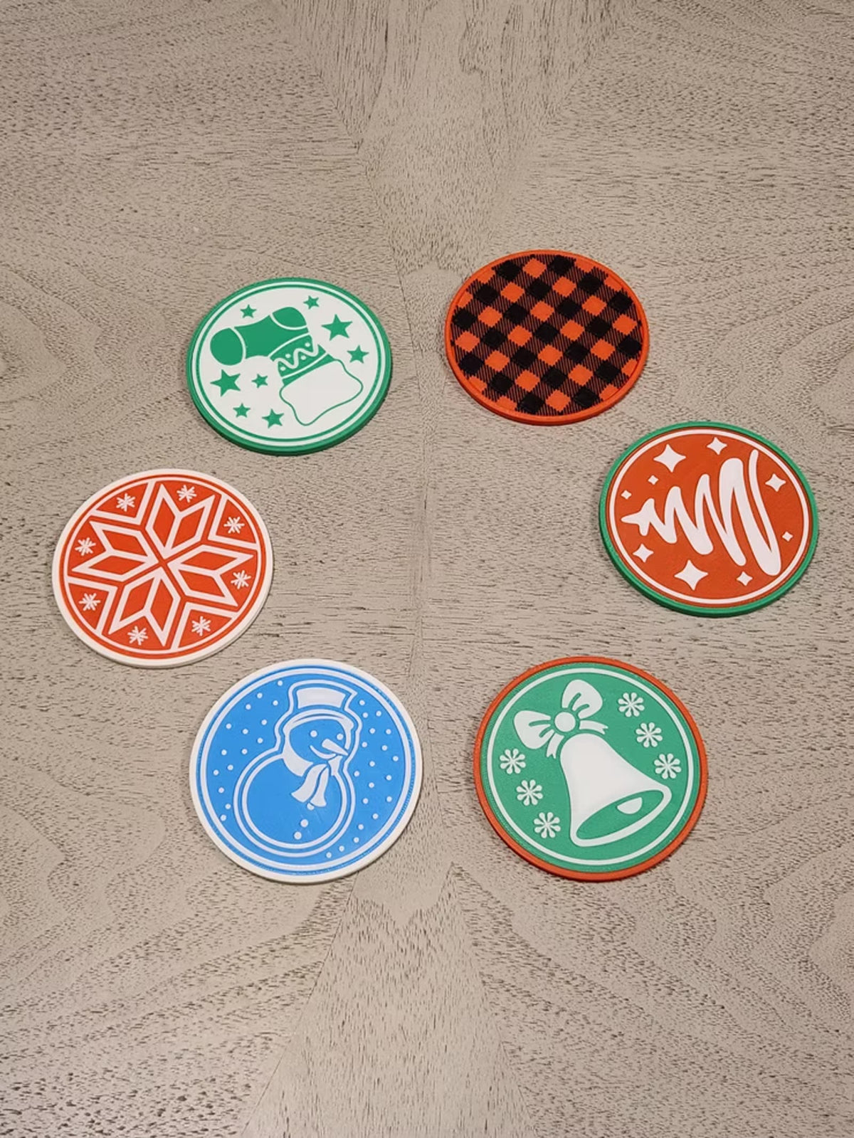 Six holiday coasters arranged on a light wood floor