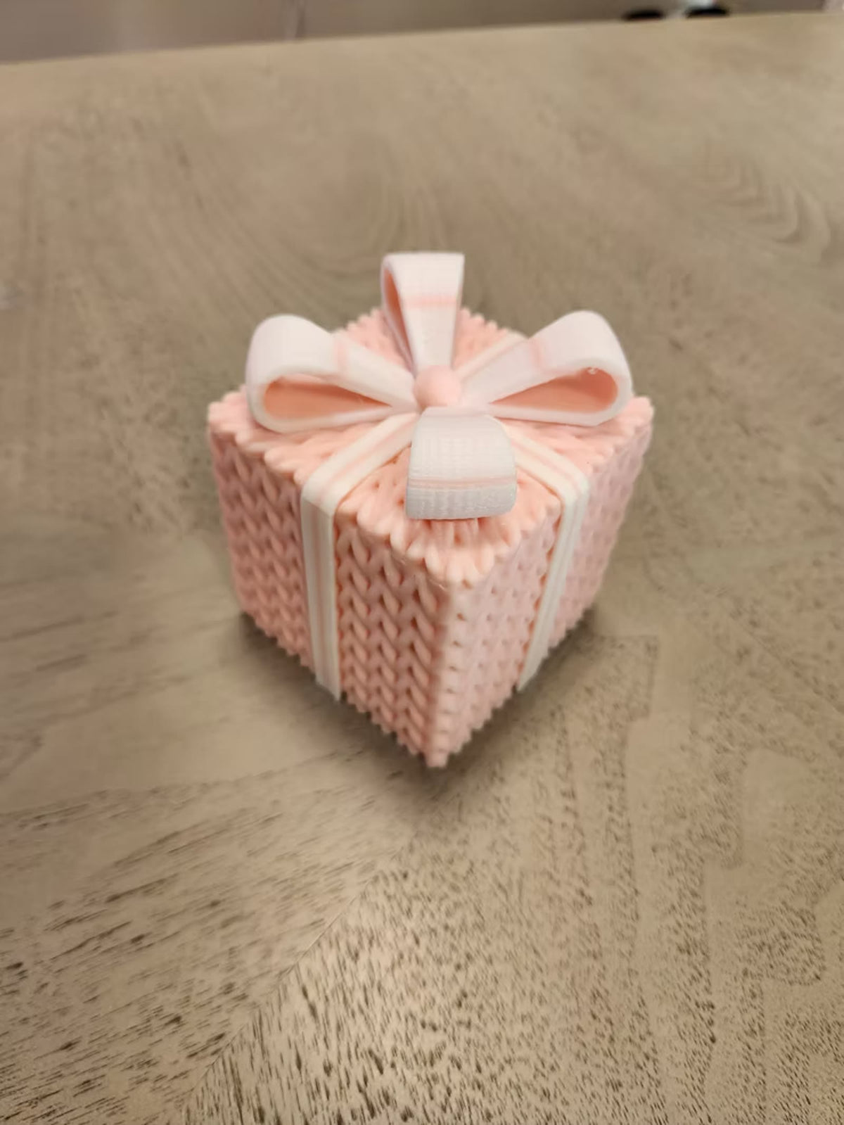 Pink knitted gift box with a white bow