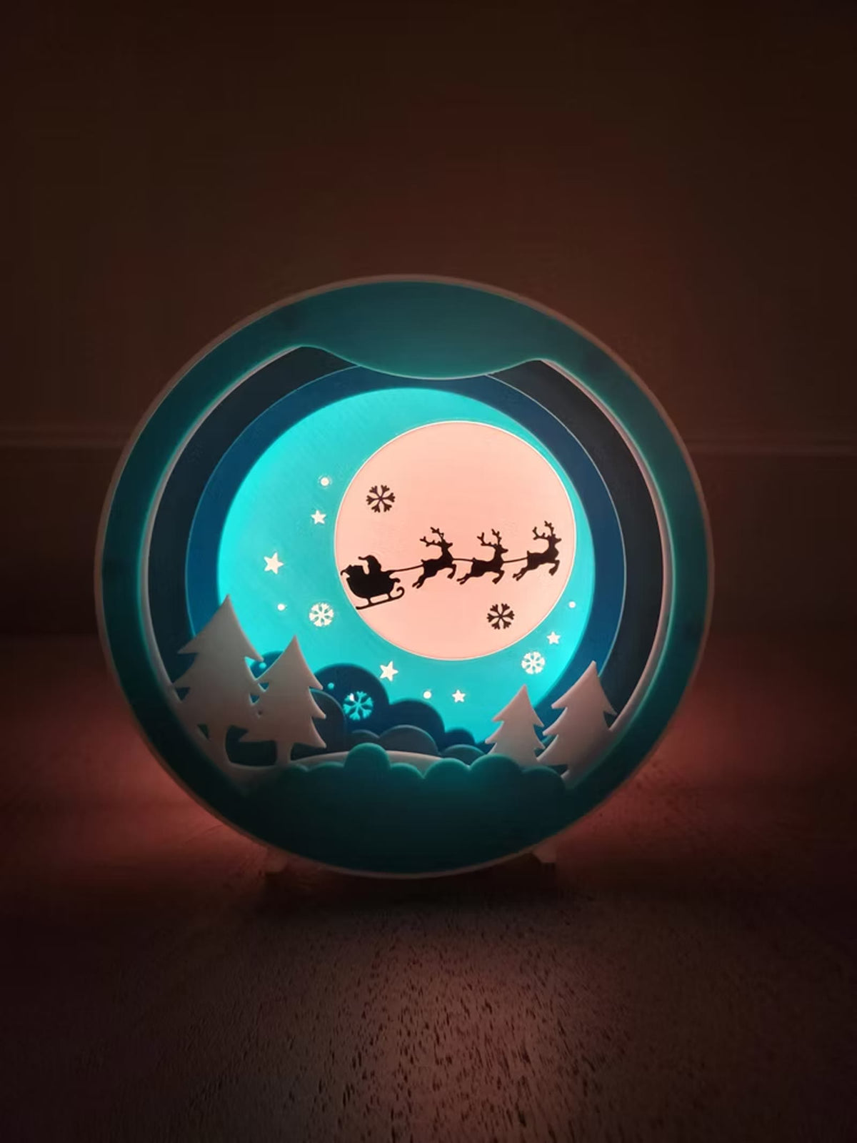 Round sleigh night light glowing teal and warm white